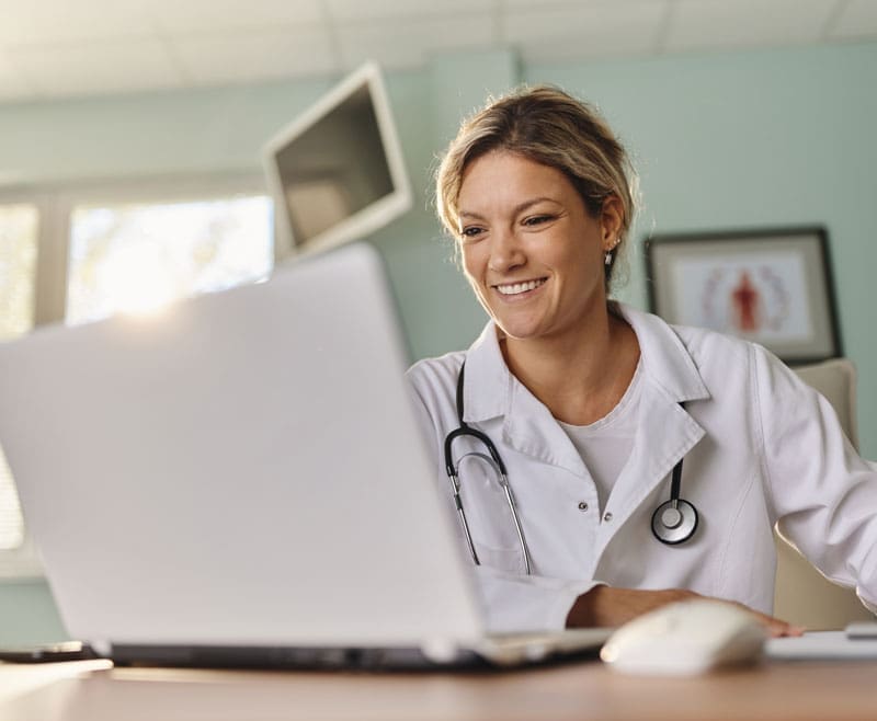 Doctor-looking-at-a-Laptop Doctor looking at her laptop smiling