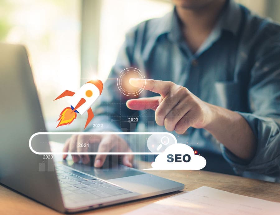 SEO-rocket someone sitting in front of laptop with a rocket taking off with SEO next to it