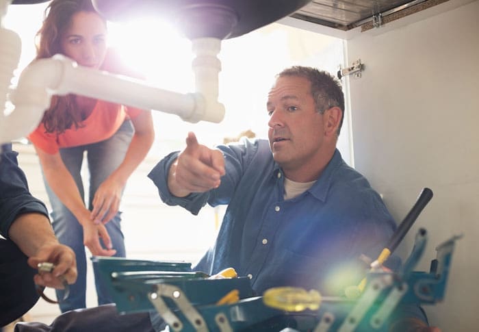 Plumber-with-customer Plumber explaining repairs to a new customer