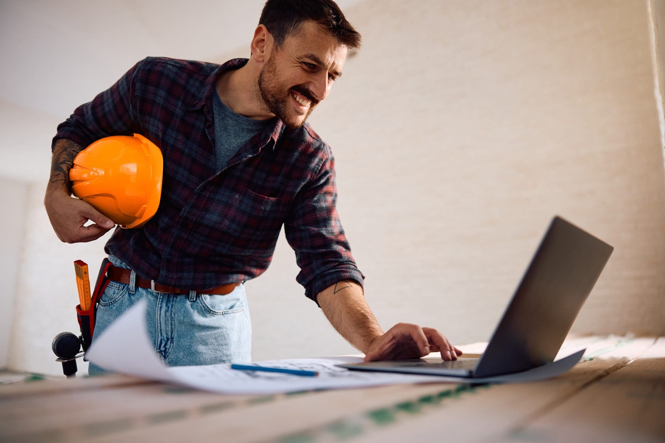 Happy worker using laptop at construction site.