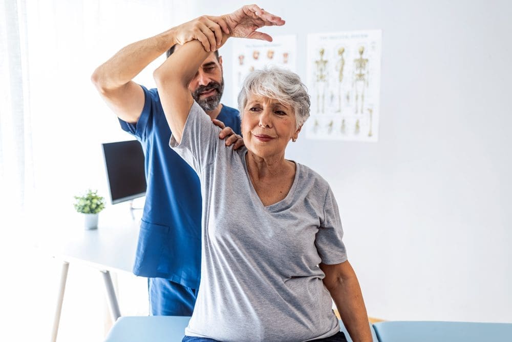 Chiropractor-with-Patient Male doctor chiropractor or osteopath fixing womans shoulder with hands movements during visit in manual therapy clinic