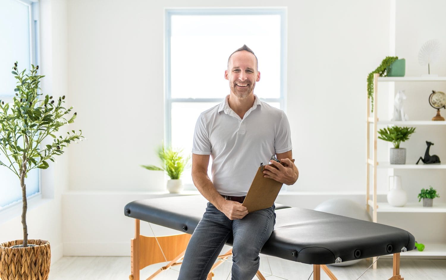 Happy-Chiropractor smiling chiropractor sitting on examination table